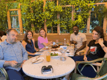 a group of people sit around a table with plates of food