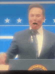 a man in a suit and tie stands behind a podium that says president of the united states on it
