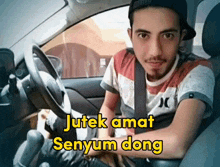 a man in a hurley shirt sits in a car