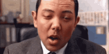 a man in a suit and tie is making a funny face while sitting in an office chair .