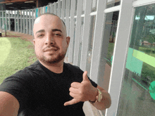 a man in a black shirt is giving a thumbs up sign