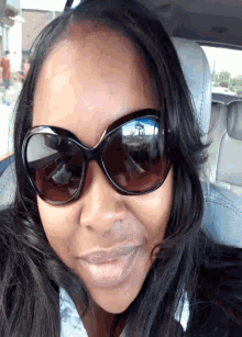 a woman wearing sunglasses is smiling while sitting in the back seat of a car