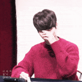 a man in a red sweater is covering his face