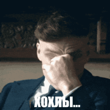 a man in a suit and tie is covering his face with his hand and the words xoxlbi written below him