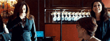 three women are standing in front of a wine rack