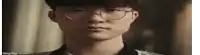 a close up of a young man wearing glasses and looking at the camera .