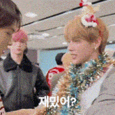 a man wearing a christmas hat and tinsel is talking to another man