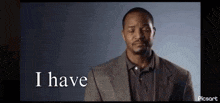 a man in a suit and polo shirt is making a funny face while saying `` i have '' .