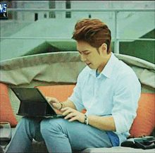 a man is sitting on a couch using a laptop with the time of 5:15 on the bottom