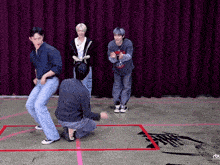 a group of young men are dancing in front of a red curtain