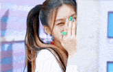 a woman covering her face with her hand while wearing a ring