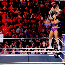 a woman in a wrestling ring with a crowd behind her and a sign that says 3:16 on it