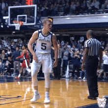a basketball player with the number 5 on his jersey is standing on the court