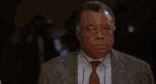 a man wearing a suit and tie is standing in a dark room .