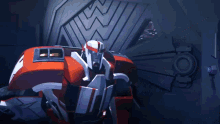 a red and white robot with blue eyes is standing in a room