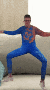 a boy in a spiderman costume is standing on his knees on a couch