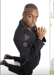 a man in a suit kneeling down with his hands folded