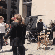 a woman wearing a mask stands in front of a director 's chair that says ' a ' on it