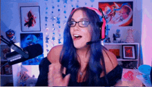 a woman wearing headphones and glasses stands in front of a shure microphone ..