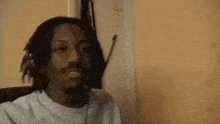a man with dreadlocks is wearing a headset and smiling while sitting in a chair .
