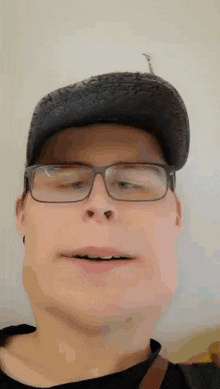 a man wearing glasses and a hat looks at the camera .