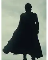a silhouette of a man wearing a cape against a cloudy sky