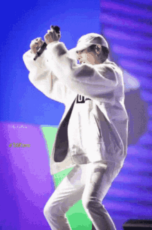 a man in a white jacket and hat is holding a microphone