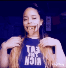 a woman wearing a blue shirt that says ta3 eht hoia sticks her tongue out