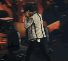 a man in a striped jacket holds a microphone in his hand while walking