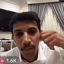 a man wearing ear buds and a white shirt with 1.6k written on the bottom
