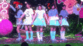 a group of girls are standing on a stage with flowers in the background ..