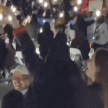 a crowd of people are gathered in a dark room with lights shining on them