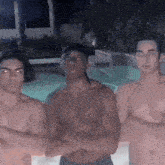 three shirtless men are posing for a picture in front of a pool