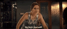 a woman in a dress is standing in front of a mirror and says `` go fuck yourself '' .