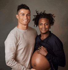 a man is holding a pregnant woman 's belly and smiling