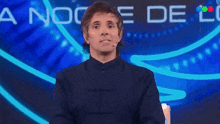 a man is clapping his hands in front of a sign that says anoche de u.
