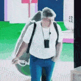 a man in a white shirt is carrying a large bag on his back