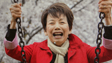 a woman in a red coat is smiling while holding a chain swing