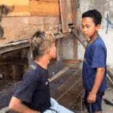 a boy in a black shirt with the letter a on it talks to another boy in a blue shirt with the letter e on it