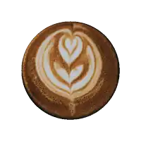 a close up of a cup of coffee with a leaf design