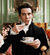 a man is holding a cup of tea and a saucer