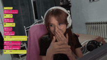 a woman wearing headphones and glasses is covering her mouth while watching a video