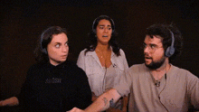 a man and two women wearing headphones with the man wearing a shirt that says swosh