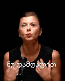 a woman in a black tank top is holding a microphone in front of a black background that says ' georgia ' on it