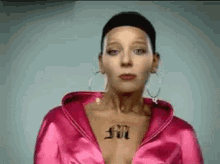 a woman with a tattoo on her chest has a pink jacket on