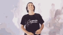 a man in a black t-shirt is dancing in front of a blurred image of a man 's face .