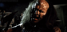 a man with blood on his face is holding a large axe in his hand