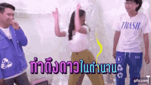 a woman in a white shirt with the word trash on it is dancing in front of two men .