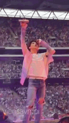 a man holding a microphone in front of a crowd with the words " viensavmoi " below him