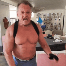 a man without a shirt is standing in front of a wall of framed pictures